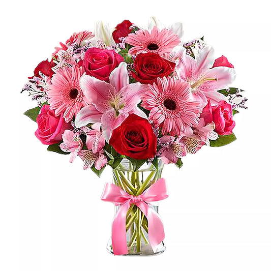 Presented in a classic clear glass vase, these radiant red and hot pink roses, lovely pink lilies, sweet pink Gerbera daisies, and more conjure up a romantic and elegant surprise.